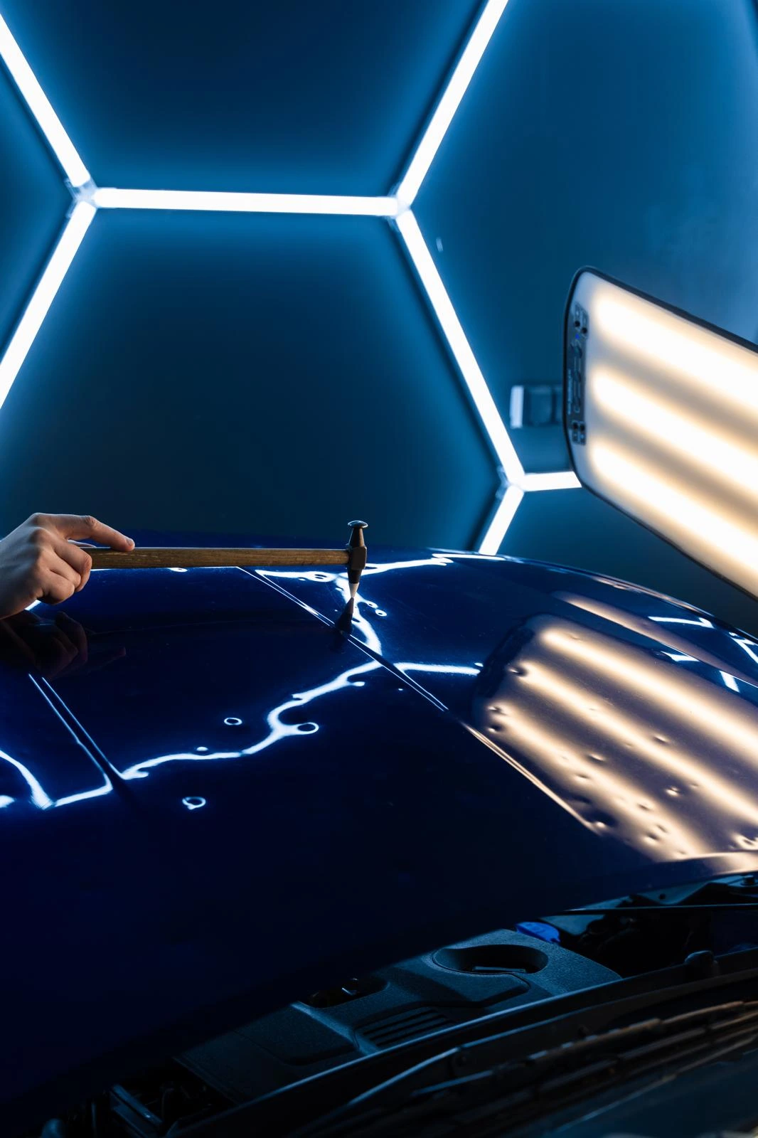 Technician using PDR light and tool on a car panel
